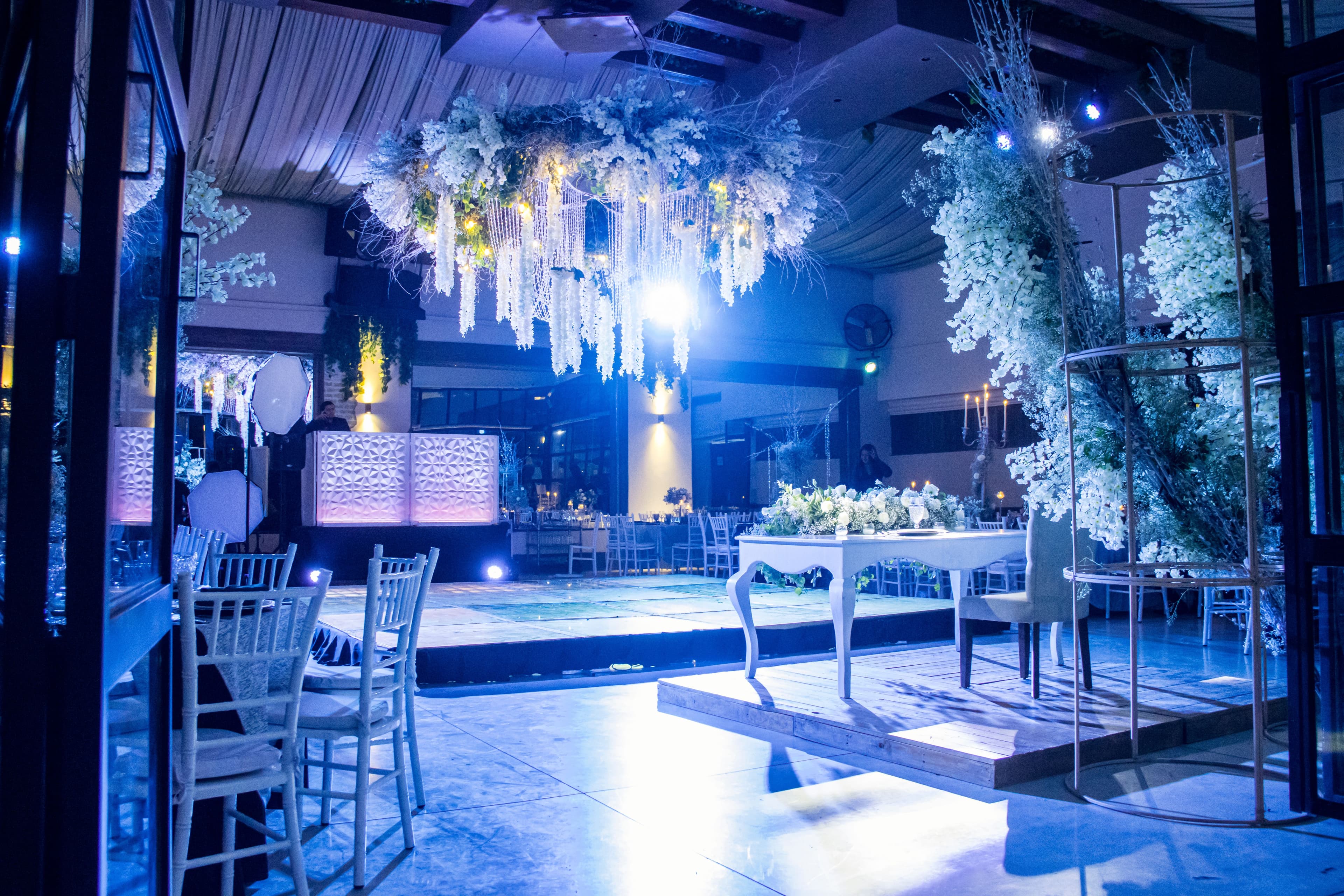 Salón de recepción con instalación floral y cabina de DJ